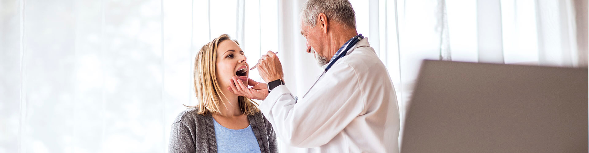 Seguro de Salud - Doctor senior examinando a una joven mujer en su consulta médica Seguro de Salud - Doctor senior examinando a una joven mujer en su consulta médica