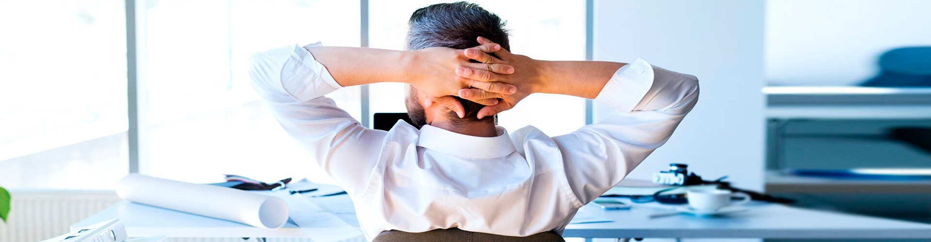 Financiación de importaciones - Un hombre con camisa sentado es su oficina mirando a la ventana con las manos en la cabeza Financiación de importaciones - Un hombre con camisa sentado es su oficina mirando a la ventana con las manos en la cabeza