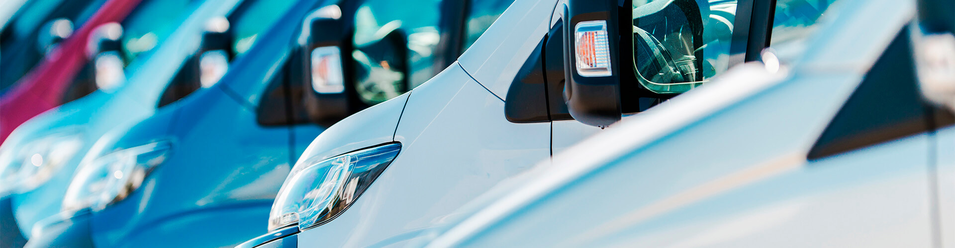 Seguro del Automovil para Empresas - Flota de furgonetas de empresa de diferentes colores aparcadas juntas entre ellas Seguro del Automovil para Empresas - Flota de furgonetas de empresa de diferentes colores aparcadas juntas entre ellas
