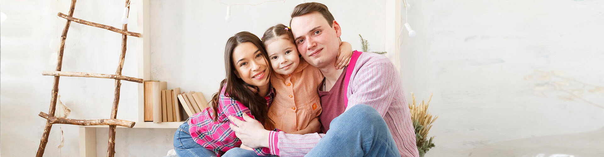 Seguro Multirriesgo de Hogar - Familia feliz y sonriendo sentada en el salón de su casa