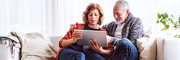 Cliente Pensión - Una pareja jubilada relajada en casa utilizando una tableta digital Cliente Pensión - Una pareja jubilada relajada en casa utilizando una tableta digital