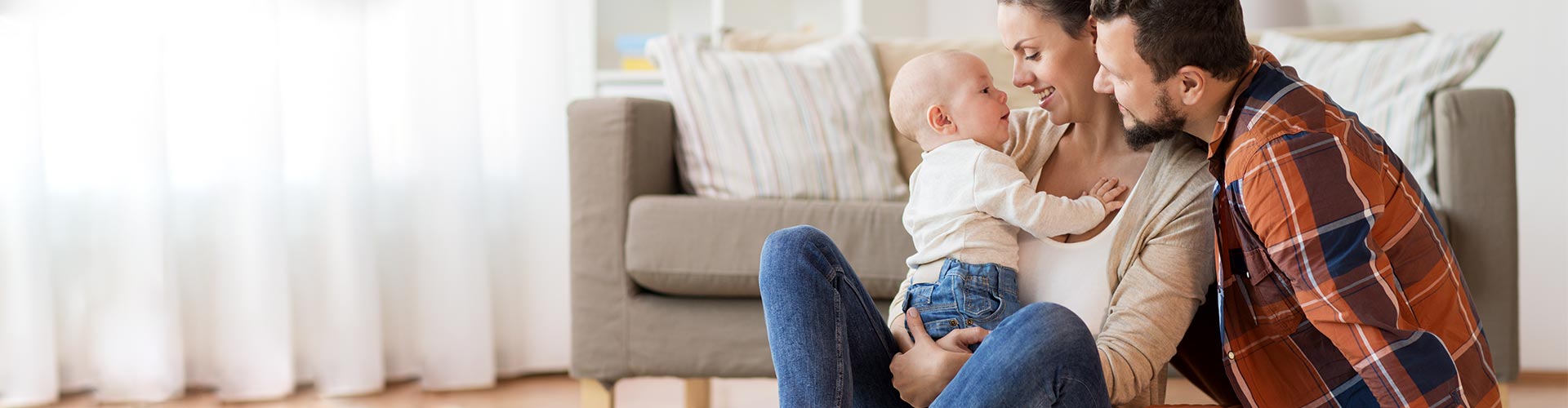 Assegurances per a Particulars - Família amb bebé asseguts en el sòl del saló de la seua casa jugant