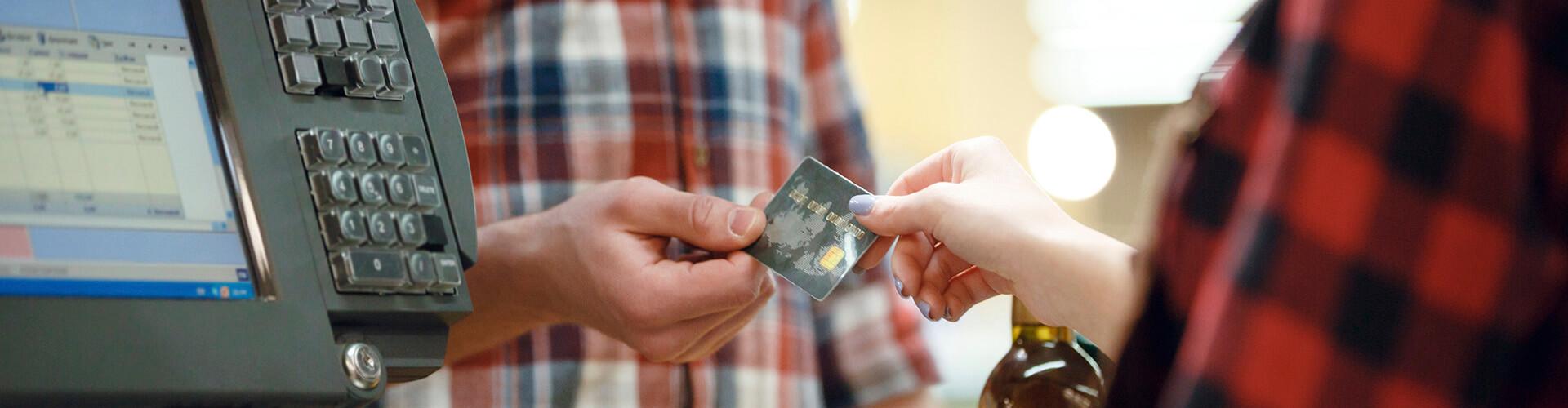 TPV Fix - Home donant una targeta de crèdit a una caixera en un supermercat al costat d'un tpv