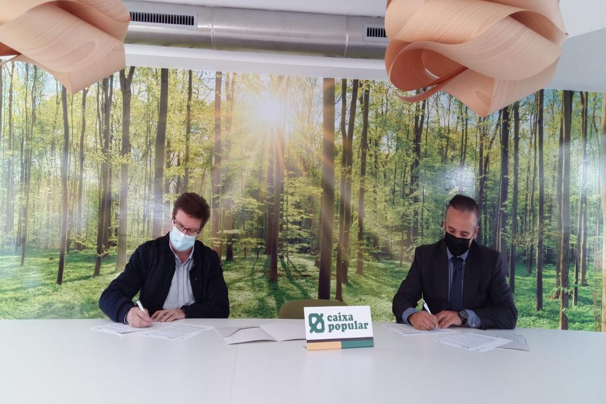 Rpresentantes de Caixa Popular y FECEVAL firmando el convenido sentados en una mesa