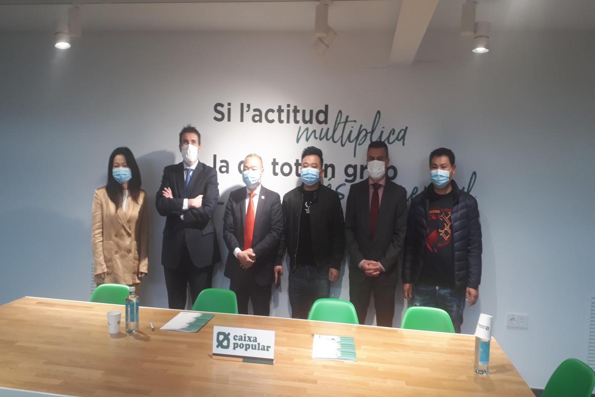 Representantes de Caja Popular y de la Asociación de Empresarios Chinos a Caixa Popular ante una mesa posando para la foto