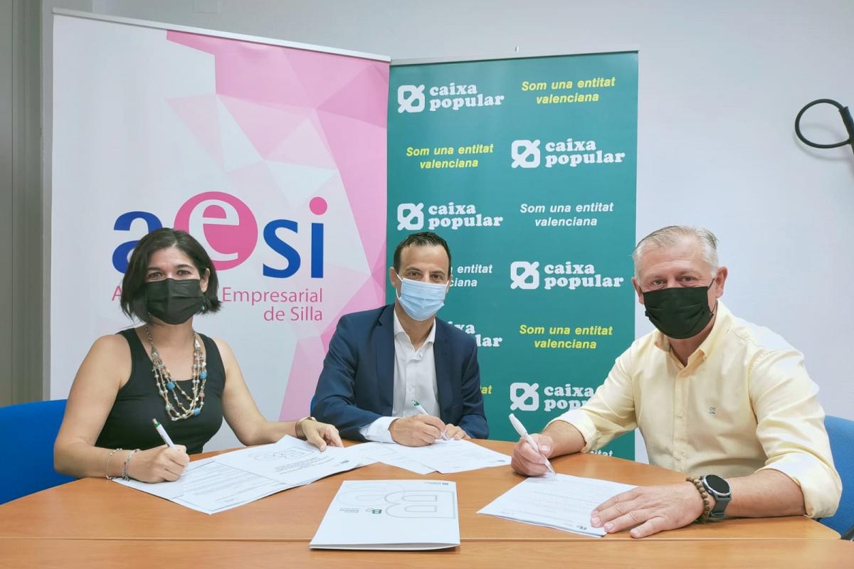 Firma del convenio entre Caixa Popular y AESI sentados en la mesa