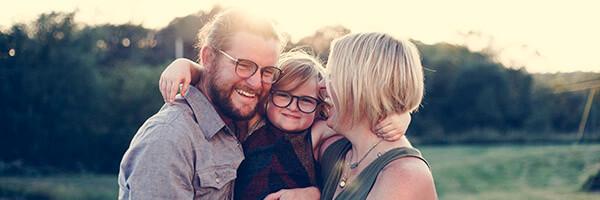Assegurança de Vida - Família feliç mentre somriuen i s'abracen en el camp
