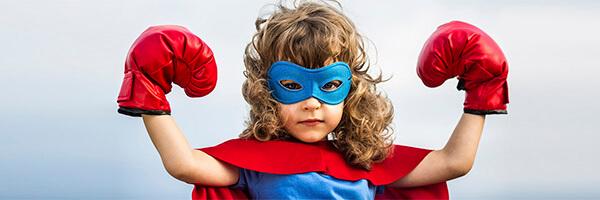 Programa En marxa Infantil - Xiquet bru amb una disfressa de superheroi amb un antifaç i guants de boxa mentre somriu