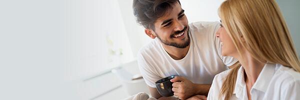 Assegurances d'Estalvi - Pareja jove feliç i enamorats en pijama, utilitzant la tablet tombats en el sofà de casa buscant assegurances d'estalvi Assegurances d'Estalvi - Pareja jove feliç i enamorats en pijama, utilitzant la tablet tombats en el sofà de casa buscant assegurances d'estalvi