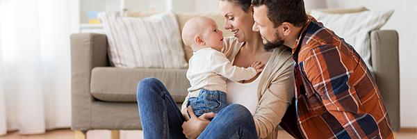 Assegurances per a Particulars - Família amb la seua bebe asseguts en el sòl del saló de la seua casa jugant