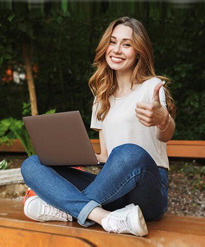 Cliente Joven In - Joven chica sonriendo sentada utilizando un portatil