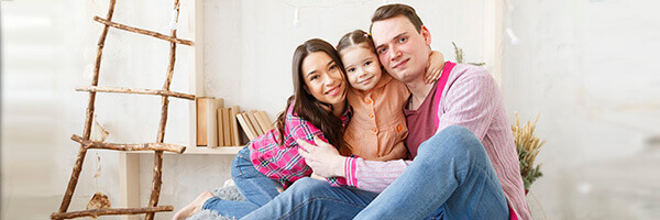 Seguro Multirriesgo de Hogar - Familia feliz sonriendo sentados en el salón de su casa Seguro Multirriesgo de Hogar - Familia feliz sonriendo sentados en el salón de su casa